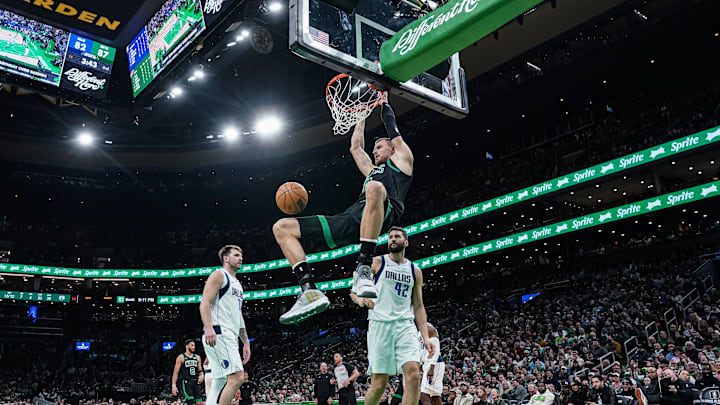 Mar 1, 2024; Boston, Massachusetts, USA; Boston Celtics center Kristaps Porzingis (8) makes the basket against Dallas Mavericks forward Maxi Kleber (42) and guard Luka Doncic (77) in the second half at TD Garden. Mandatory Credit: David Butler II-USA TODAY Sports