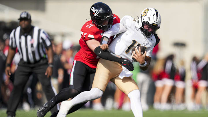 Oct 11, 2025; Cincinnati, Ohio, USA; Cincinnati Bearcats linebacker Jake Golday (11) attempts to tackle UCF Knights quarterback Cam Fancher (14) in the second half at Nippert Stadium. 