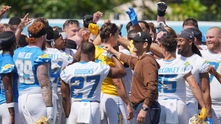 Jun 13, 2024; Costa Mesa, CA, USA; Los Angeles Chargers coach Jim Harbaugh joins hands in a huddle with tight end Donald Parham Jr. (89), running back J.K. Dobbins (27), quarterback Justin Herbert (10) and receiver Ladd McConkey (15) during minicamp at the Hoag Performance Center. Mandatory Credit: Kirby Lee-USA TODAY Sports
