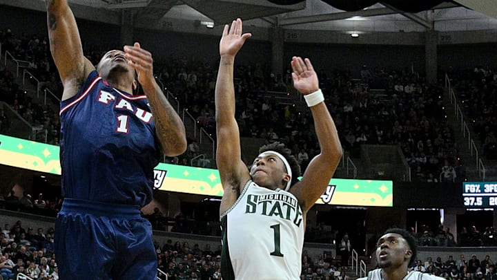 Dec 21, 2024; East Lansing, Michigan, USA;  Florida Atlantic Owls forward Kaleb Glenn (1) scores against Michigan State Spartans guard Jeremy Fears Jr. (1) during the first half at Jack Breslin Student Events Center. Mandatory Credit: Dale Young-Imagn Images