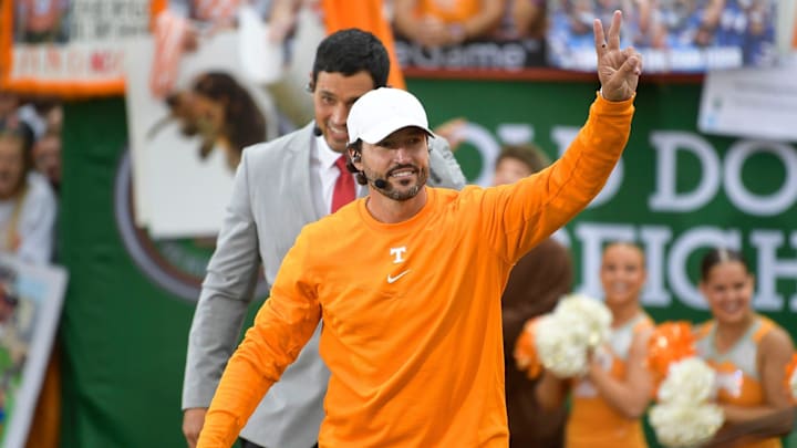 Tennessee baseball head coach Tony Vitello walks in an orange sweatshirt and white hat waving to fans