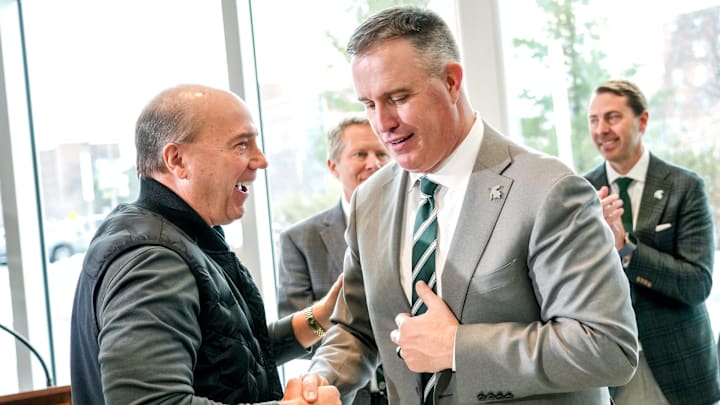 Greg Williams, left, shakes hands with Michigan State's new football coach Pat Fitzgerald during an introductory press conference on Tuesday, Dec. 2, 2025, at the Tom Izzo Football Building in East Lansing.