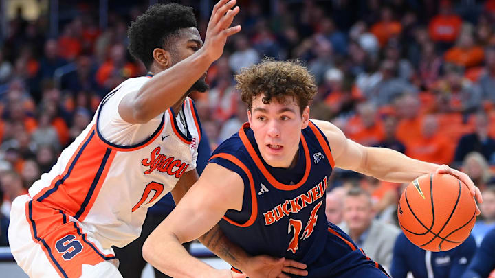 Dec 28, 2024; Syracuse, New York, USA; Bucknell Bison guard Achile Spadone (24) drives to the basket as Syracuse Orange guard Kyle Cuffe Jr. (0) defends during the second half at the JMA Wireless Dome. Mandatory Credit: Rich Barnes-Imagn Images