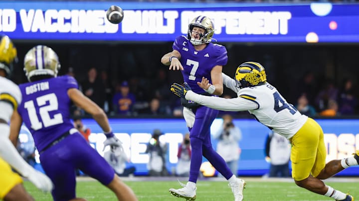 Huskies quarterback Will Rogers (7) gets a pass off under pressure from Michigan defensive end TJ Guy (42).