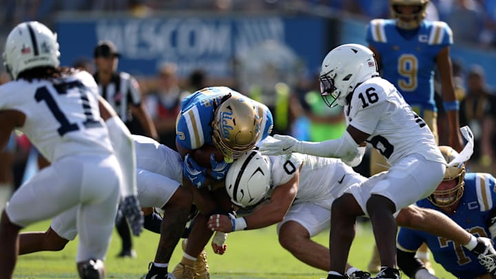UCLA Bruins running back Jalen Berger is tackled by Penn State Nittany Lions cornerback AJ Harris (4) and linebacker Dominic Deluca (0) during the fourth quarter.