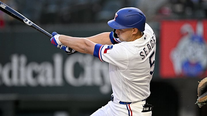 Corey Seager swings a bat in a white Rangers unifor