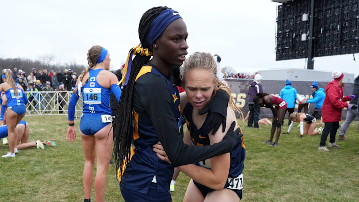 Joy Naukot, who took home a bronze medal at the NCAA Track and Field Championships on Thursday night, huddles with a teammate at a cross country meet.