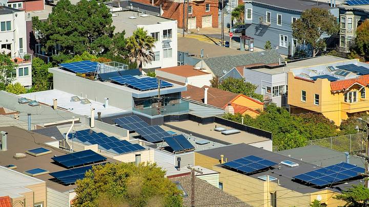 Residential rooftops outfitted with solar panel arrays across a San Francisco neighborhood.