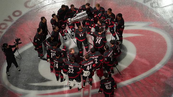 Sep 29, 2026; Raleigh, North Carolina, USA;  Carolina Hurricanes players surround the Stanley Cup being hoisted by center Jordan Staal (11) before a banner-raising ceremony prior to a game against the Florida Panthers at Lenovo Center.  Mandatory Credit: James Guillory-Imagn Images
