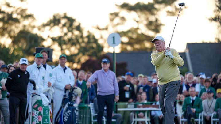 Jack Nicklaus hits his honorary tee shot Thursday morning while Gary Player and Tom Watson watch.