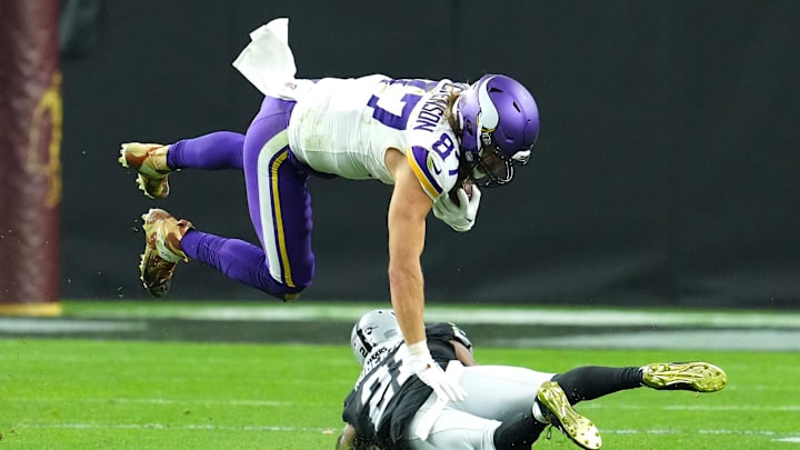 Dec 10, 2023; Paradise, Nevada, USA; Minnesota Vikings tight end T.J. Hockenson (87) is upended by Las Vegas Raiders cornerback Amik Robertson (21) during the fourth quarter at Allegiant Stadium.