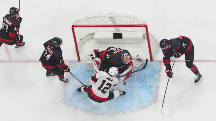 Apr 20, 2026; Raleigh, North Carolina, USA; Ottawa Senators center Shane Pinto (12) scoring chance is stopped by Carolina Hurricanes goaltender Frederik Andersen (31) defenseman Sean Walker (26) and defenseman Jaccob Slavin (74) during the second overtime in game two of the first round of the 2026 Stanley Cup Playoffs at Lenovo Center. Mandatory Credit: James Guillory-Imagn Images