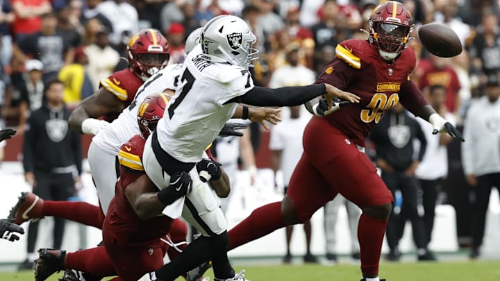 Sep 21, 2025; Landover, Maryland, USA; Las Vegas Raiders quarterback Geno Smith (7) passes the ball while being tackled by Washington Commanders nose tackle Daron Payne (94) during the second quarter at Northwest Stadium. Mandatory Credit: Geoff Burke-Imagn Images