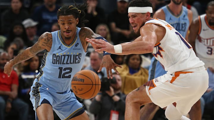 Feb 25, 2025; Memphis, Tennessee, USA; Memphis Grizzlies guard Ja Morant (12) steals the ball from Phoenix Suns guard Devin Booker (1) during the second quarter at FedExForum. Mandatory Credit: Petre Thomas-Imagn Images