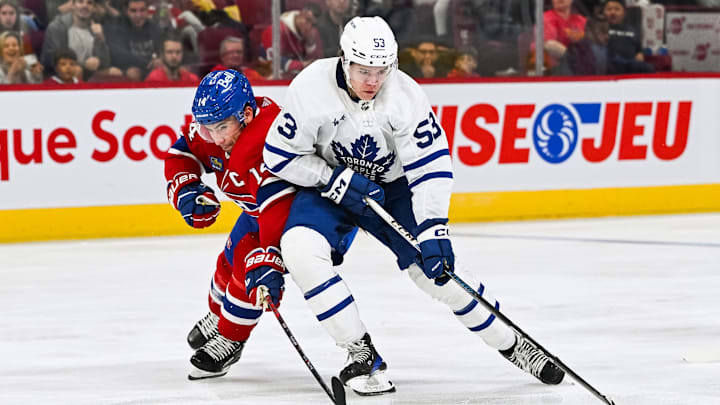 Sep 30, 2023; Montreal, Quebec, CAN; Toronto Maple Leafs right wing Easton Cowan (53) plays the puck against Montreal Canadiens center Nick Suzuki (14) during the third period at Bell Centre. Mandatory Credit: David Kirouac-Imagn Images