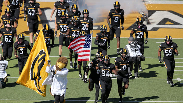 Oct 16, 2021; Hattiesburg, Mississippi, USA; The Southern Miss Golden Eagles mascot and Southern Miss Golden Eagles defensive lineman Kristin Booth (94) lead the team onto the field before their game against the UAB Blazers at M.M. Roberts Stadium. Mandatory Credit: Chuck Cook-Imagn Images