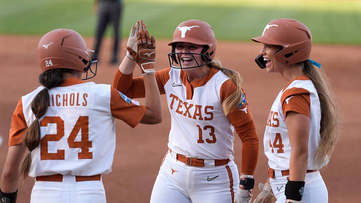 Texas Longhorns' Hannah Wells (13) celebrates with infielder Jaycie Nichols (24) and Kaiah Altmeyer (44) after scoring a run in the first inning of Game 1 of the NCAA softball Women's College World Series finals between the Texas Longhorns and the Texas Tech Red Raiders at Devon Park in Oklahoma City, Wednesday, June 3, 2026.