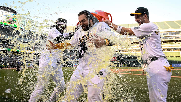 Sep 2, 2024; Oakland, California, USA; Oakland Athletics outfielder Lawrence Butler (left) and shortstop Max Schuemann (right) douse catcher Shea Langeliers (center) after his walk-off home run against the Seattle Mariners at Oakland-Alameda County Coliseum. Mandatory Credit: Eakin Howard-Imagn Images