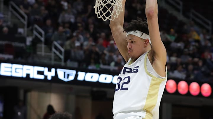 Akron Zips forward James Okonkwo (32) hangs on the rim after a dunk during the second half of an NCAA college basketball game in the semifinals of the Mid-American Conference Tournament at Rocket Arena on Friday, March 14, 2025, in Cleveland, Ohio.