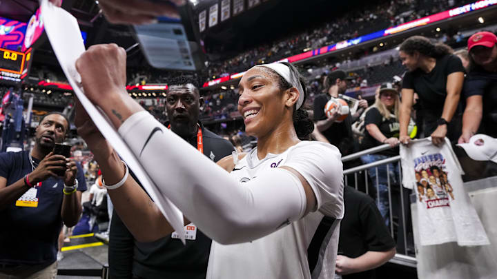 Sep 13, 2024; Indianapolis, Indiana, USA; Las Vegas Aces center A'ja Wilson (22) signs a poster Friday, Sept. 13, 2024, during a game between the Indiana Fever and the Las Vegas Aces on Friday, Sept. 13, 2024, at Gainbridge Fieldhouse in Indianapolis. The Aces defeated the Fever, 78-74. Sep 13, 2024; Indianapolis, Indiana, USA; Las Vegas Aces center A'ja Wilson (22) signs a poster Friday, Sept. 13, 2024, during a game between the Indiana Fever and the Las Vegas Aces on Friday, Sept. 13, 2024, at Gainbridge Fieldhouse in Indianapolis. The Aces defeated the Fever, 78-74.