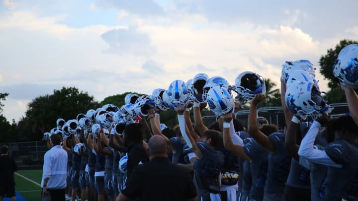 Wellington Wolves football players raising their helmets pregame during the 2023 season
