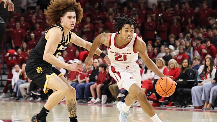 Feb 21, 2026; Fayetteville, Arkansas, USA; Arkansas Razorbacks guard D.J. Wagner (21) drives against Missouri Tigers guard T.O. Barrett (5) during the first half at Bud Walton Arena. 