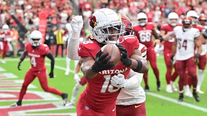 Sep 29, 2024; Glendale, Arizona, USA;  Arizona Cardinals wide receiver Marvin Harrison Jr. (18) catches a touchdown  as Washington Commanders cornerback Noah Igbinoghene (1) defends in the first half at State Farm Stadium. Mandatory Credit: Matt Kartozian-Imagn Images