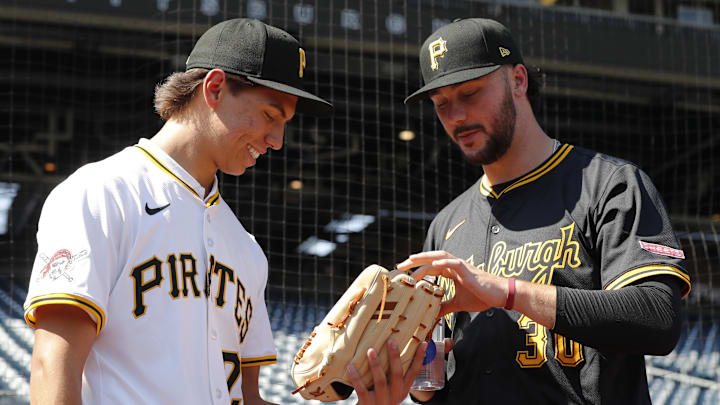 Jul 22, 2025; Pittsburgh, Pennsylvania, USA;  Seth Hernandez (left) the Pittsburgh Pirates first round and number six overall pick in the 2025 first year player draft looks at the glove of Pirates pitcher Paul Skenes (30) before the game against the Detroit Tigers at PNC Park. Mandatory Credit: Charles LeClaire-Imagn Images