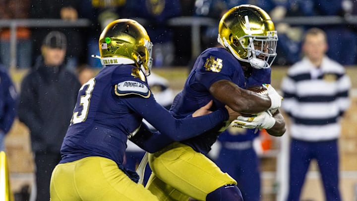 Nov 8, 2025; South Bend, Indiana, USA; Notre Dame Fighting Irish quarterback CJ Carr (13) hands off to running back Jeremiyah Love (4) against the Navy Midshipmen during the first half at Notre Dame Stadium. Mandatory Credit: Michael Caterina-Imagn Images