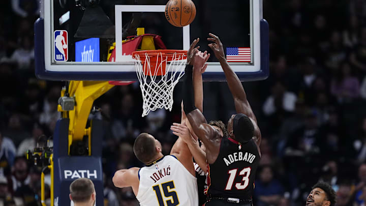 Nov 5, 2025; Denver, Colorado, USA; Miami Heat center Bam Adebayo (13) and Denver Nuggets center Nikola Jokic (15) reach for the rebound in the first quarter at Ball Arena. Mandatory Credit: Ron Chenoy-Imagn Images