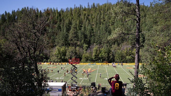 Arizona State University fan Ed O'Brien, who has been a fan for over 40 years, takes a sip of water while watching practice from a hill on Aug. 7, 2024 at Camp Tontozona in Payson, Arizona. Arizona State University fan Ed O'Brien, who has been a fan for over 40 years, takes a sip of water while watching practice from a hill on Aug. 7, 2024 at Camp Tontozona in Payson, Arizona.