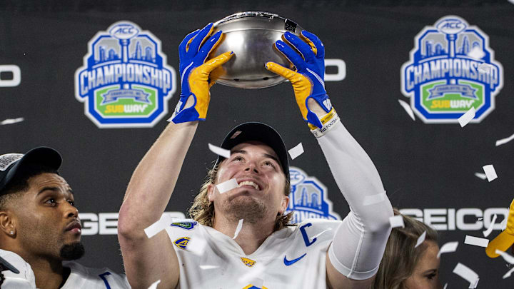 Dec 4, 2021; Charlotte, NC, USA; Pittsburgh Panthers quarterback Kenny Pickett (8) holds up the championship trophy as head coach Pat Narduzzi looks on after winning the ACC championship game at Bank of America Stadium. Mandatory Credit: Bob Donnan-Imagn Images