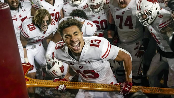 Nov 25, 2023; Minneapolis, Minnesota, USA; Wisconsin Badgers wide receiver Chimere Dike (13) chops down the Minnesota Golden Gophers goal post with Paul Bunyan's Axe to celebrate after a 28-14 victory to claim the rivalry trophy at Huntington Bank Stadium.
