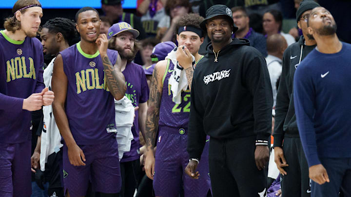 Mar 30, 2025; New Orleans, Louisiana, USA; New Orleans Pelicans forward Zion Williamson, wearing street clothes and hat, smiles as his team gains a lead late during the fourth quarter against the Charlotte Hornets at Smoothie King Center. Mandatory Credit: Matthew Hinton-Imagn Images