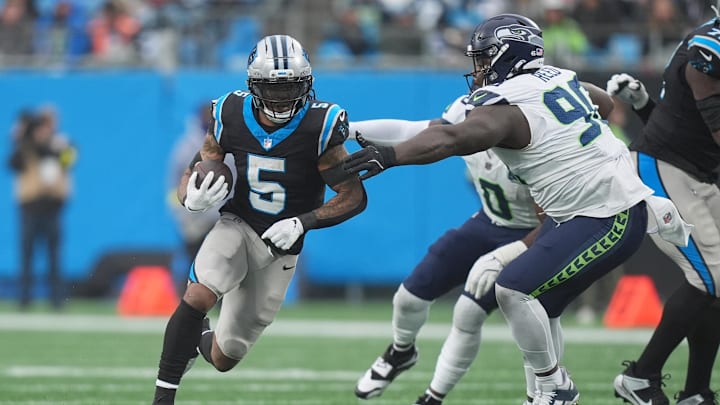 Dec 28, 2025; Charlotte, North Carolina, USA; Carolina Panthers running back Rico Dowdle (5) runs the ball against Seattle Seahawks defensive tackle Jarran Reed (90) during the third quarter at Bank of America Stadium. Mandatory Credit: Jim Dedmon-Imagn Images