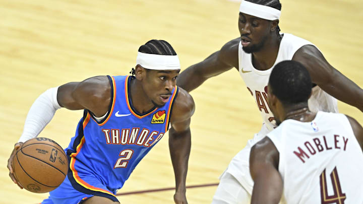 Oct 27, 2023; Cleveland, Ohio, USA; Oklahoma City Thunder guard Shai Gilgeous-Alexander (2) moves against Cleveland Cavaliers guard Caris LeVert (3) and forward Evan Mobley (4) in the first quarter at Rocket Mortgage FieldHouse. Mandatory Credit: David Richard-Imagn Images Oct 27, 2023; Cleveland, Ohio, USA; Oklahoma City Thunder guard Shai Gilgeous-Alexander (2) moves against Cleveland Cavaliers guard Caris LeVert (3) and forward Evan Mobley (4) in the first quarter at Rocket Mortgage FieldHouse. Mandatory Credit: David Richard-Imagn Images