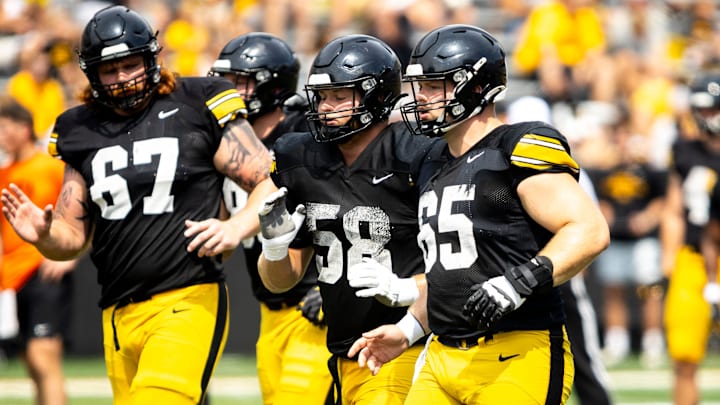 Aug 9, 2025; Iowa offensive linemen Gennings Dunker (67) Kade Pieper (58) and Logan Jones (65) run a drill during the Hawkeyes Kids Day NCAA football open practice at Kinnick Stadium in Iowa City, Iowa. Mandatory Credit: Joseph Cress for the Des Moines Register