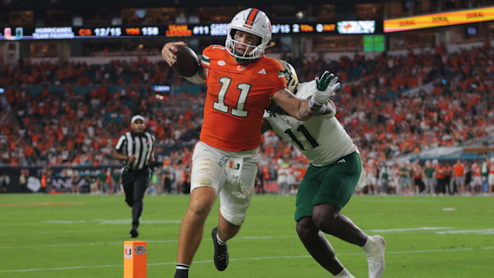 Sep 13, 2025; Miami Gardens, Florida, USA; Miami Hurricanes quarterback Carson Beck (11) carries the football for a touchdown against South Florida Bulls fullback D.J. Harris (11) during the second quarter at Hard Rock Stadium. Mandatory Credit: Sam Navarro-Imagn Images