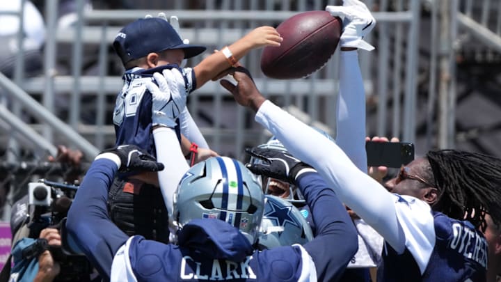 Dallas Cowboys defenders celebrate an interception with a child during training camp in Oxnard. 