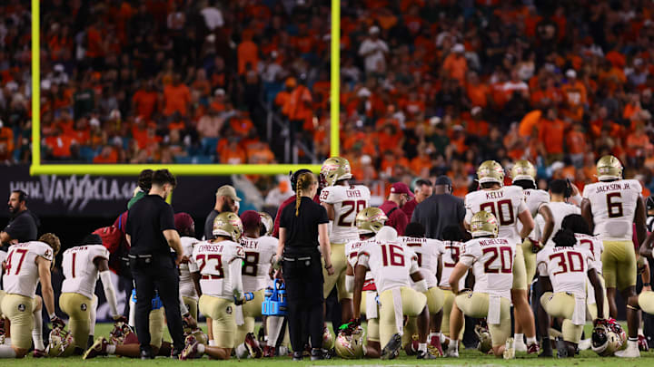 Oct 26, 2024; Miami Gardens, Florida, USA; Florida State Seminoles players take a knee around defensive back Ashlynd Barker (not pictured) after an injury against the Miami Hurricanes during the fourth quarter at Hard Rock Stadium. Mandatory Credit: Sam Navarro-Imagn Images