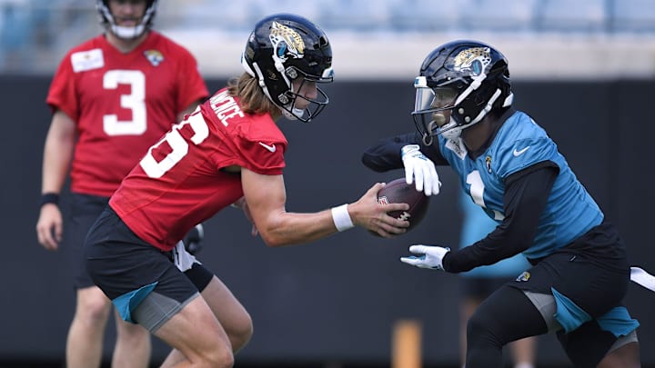 Jacksonville Jaguars quarterback Trevor Lawrence (16) fakes a handoff to running back Travis Etienne.