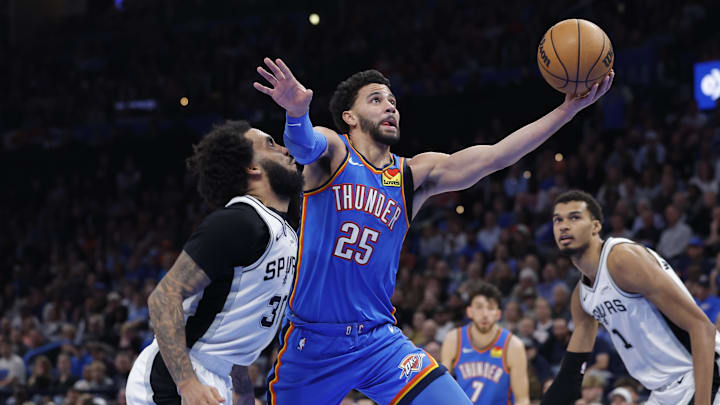 Jan 13, 2026; Oklahoma City, Oklahoma, USA; Oklahoma City Thunder guard Ajay Mitchell (25) goes to the basket beside San Antonio Spurs forward Julian Champagnie (30) during the second half at Paycom Center. Mandatory Credit: Alonzo Adams-Imagn Images