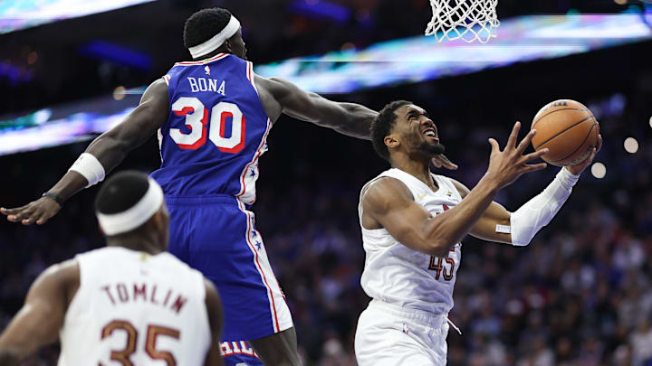 Jan 14, 2026; Philadelphia, Pennsylvania, USA; Cleveland Cavaliers guard Donovan Mitchell (45) is fouled while driving for a shot past Philadelphia 76ers center Adem Bona (30) during the third quarter at Xfinity Mobile Arena. Mandatory Credit: Bill Streicher-Imagn Images