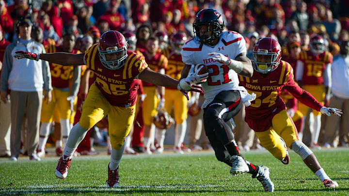 Nov 22, 2014; Ames, IA, USA; Texas Tech Red Raiders running back DeAndre Washington (21) escapes Iowa State Cyclones linebacker Brian Mills (25) and defensive back Nigel Tribune (34) at Jack Trice Stadium. Mandatory Credit: Steven Branscombe-Imagn Images