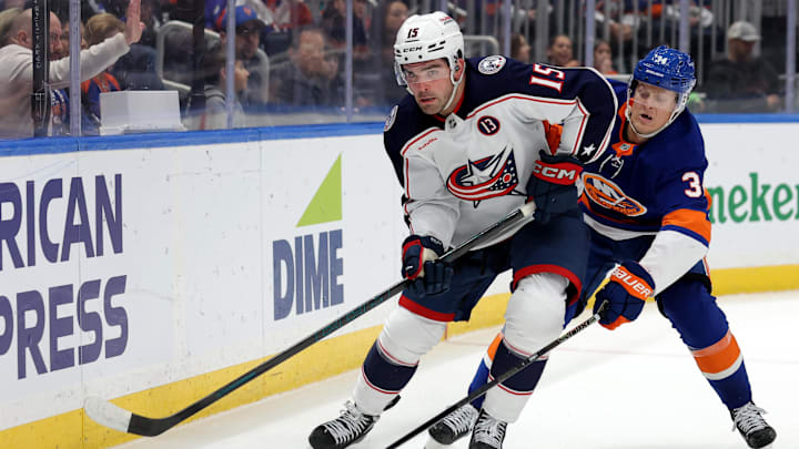 Mar 24, 2025; Elmont, New York, USA; Columbus Blue Jackets defenseman Dante Fabbro (15) skates with the puck against New York Islanders defenseman Adam Boqvist (34) during the second period at UBS Arena. Mandatory Credit: Brad Penner-Imagn Images