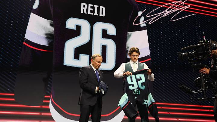 Jun 26, 2026; Buffalo, New York, USA; Chase Reid reacts beside NHL commissioner Gary Bettman after being selected with the seventh pick in the first round of the 2026 NHL Draft by the Seattle Kraken at KeyBank Center. Mandatory Credit: Timothy T. Ludwig-Imagn Images