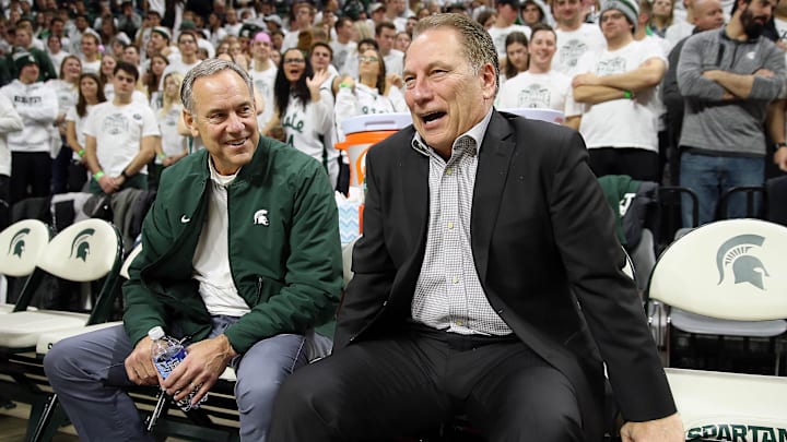 Nov 18, 2019; East Lansing, MI, USA; Michigan State Spartans head basketball coach Tom Izzo(right) and Michigan State Spartans head football coach Mark Dantonio sit on the sidelines prior to a game between the Michigan State Spartans and the Duke Blue Devils at Breslin Center. Mandatory Credit: Mike Carter-Imagn Images