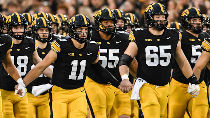 Oct 18, 2025; Iowa City, Iowa, USA; Iowa Hawkeyes quarterback Mark Gronowski (11) and offensive lineman Logan Jones (65) leads the offense onto the field before the game against the Penn State Nittany Lions at Kinnick Stadium. Mandatory Credit: Jeffrey Becker-Imagn Images Oct 18, 2025; Iowa City, Iowa, USA; Iowa Hawkeyes quarterback Mark Gronowski (11) and offensive lineman Logan Jones (65) leads the offense onto the field before the game against the Penn State Nittany Lions at Kinnick Stadium. Mandatory Credit: Jeffrey Becker-Imagn Images