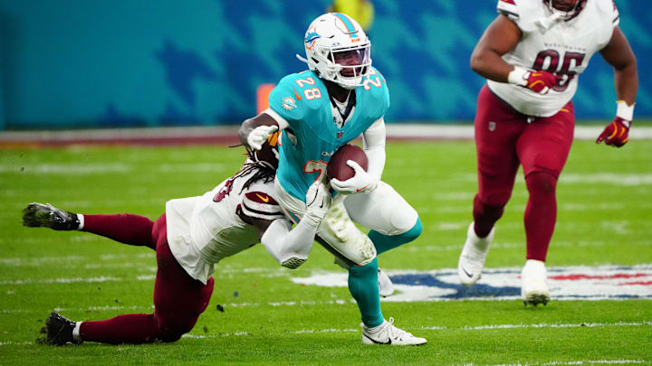 Miami Dolphins running back De'Von Achane (28) carries the ball defended by Washington Commanders linebacker Jordan Magee (58) in the second quarter during the 2025 NFL Madrid Game at Santiago Bernabeu Stadium.