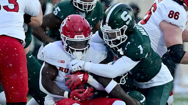 Nov 30, 2024; East Lansing, Michigan, USA;  Rutgers Scarlet Knights running back Kyle Monangai (5) is tackled by Michigan State Spartans defensive back Nikai Martinez (1) and linebacker Jordan Turner (7) during the first quarter at Spartan Stadium. Mandatory Credit: Dale Young-Imagn Images